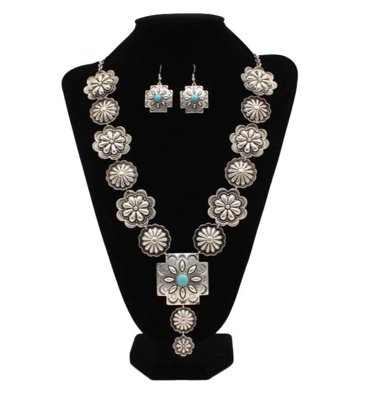 Silver and turquoise jewelry set with necklace and earrings on a black stand