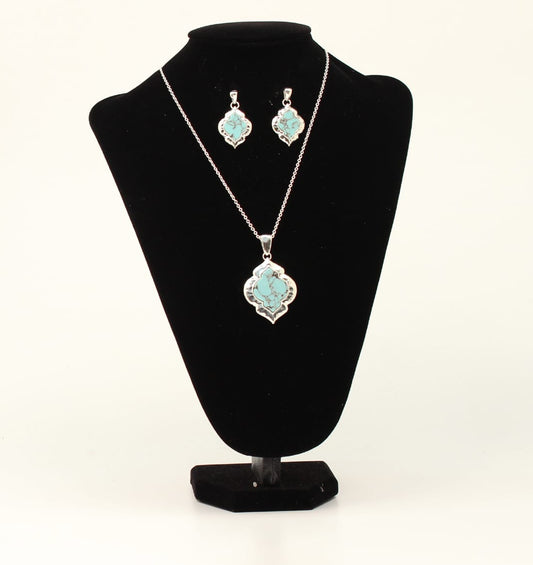 Jewelry set with turquoise pendant necklace and earrings on a black stand against a white background
