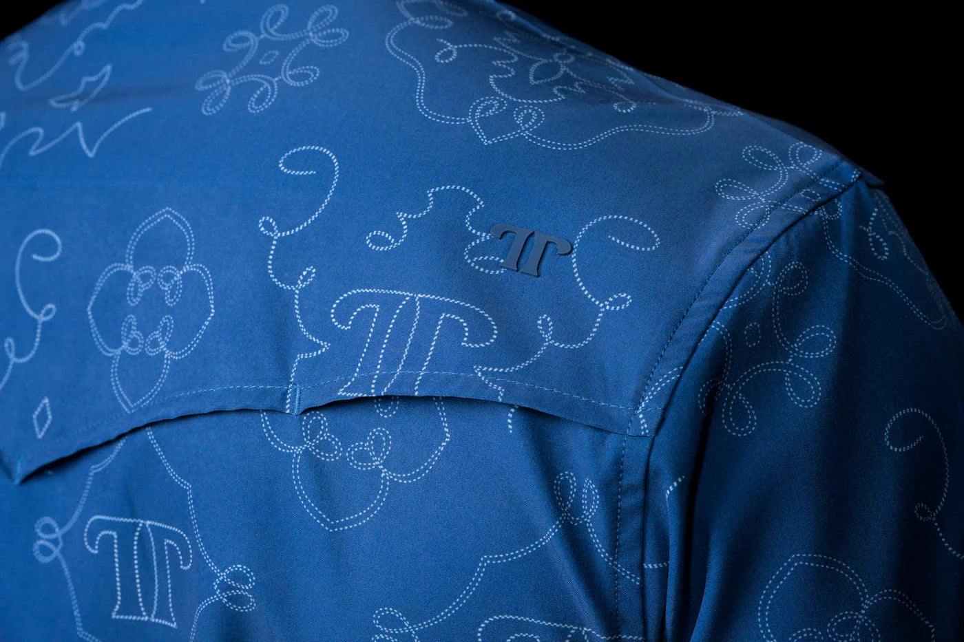 View of back yoke of a blue shirt with white pattern and Ferrell Brand logo on a black background