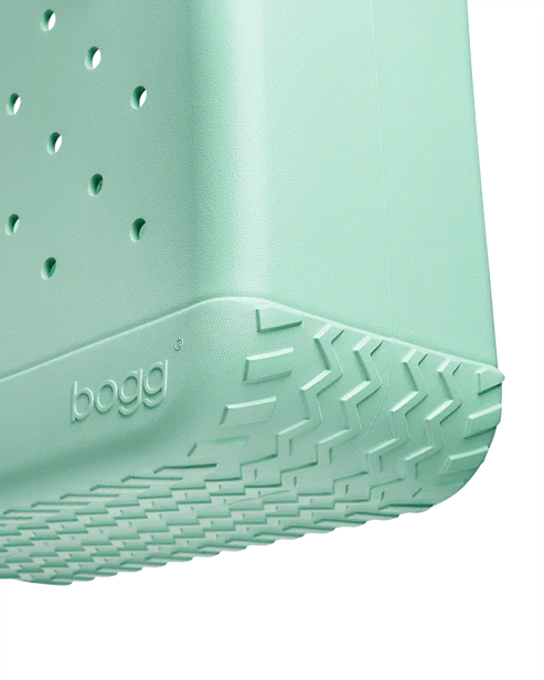 Close-up of a seafoam Bogg bag with branding on a white background