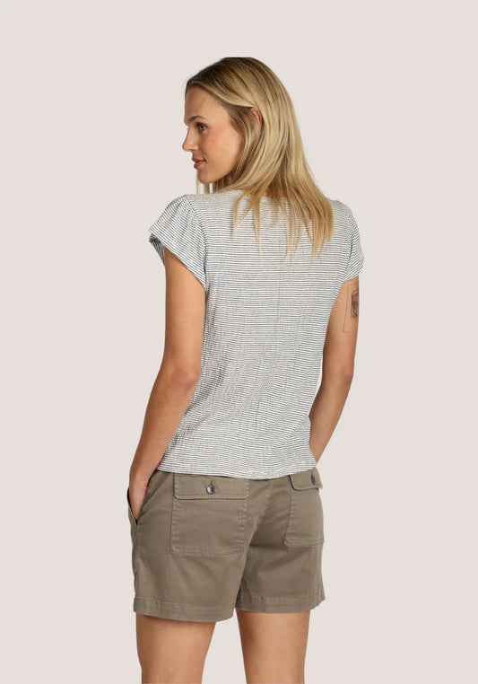 Back view of woman wearing a striped shirt and beige shorts on a cream background