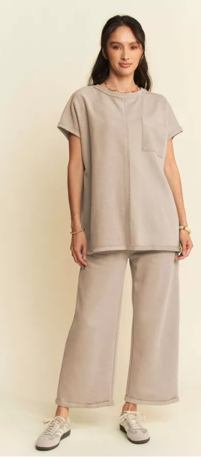 A female model wearing a dark beige terry mixed top and pants set, with a chest pocket and elastic waistband.