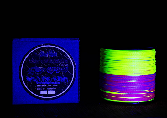 Spool of glow-in-the-dark fishing line next to packaging on a dark background
