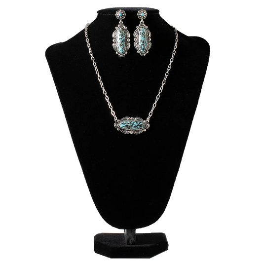 Silver and turquoise jewelry set with necklace and earrings on a black bust