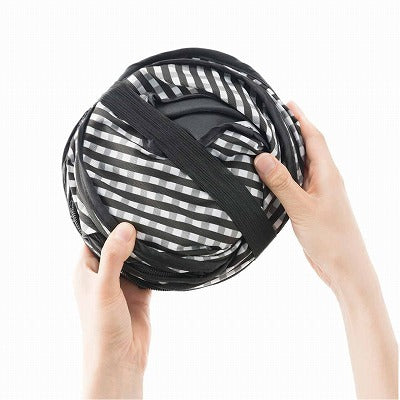 Folded black and white cat carrier held by hands on a white background