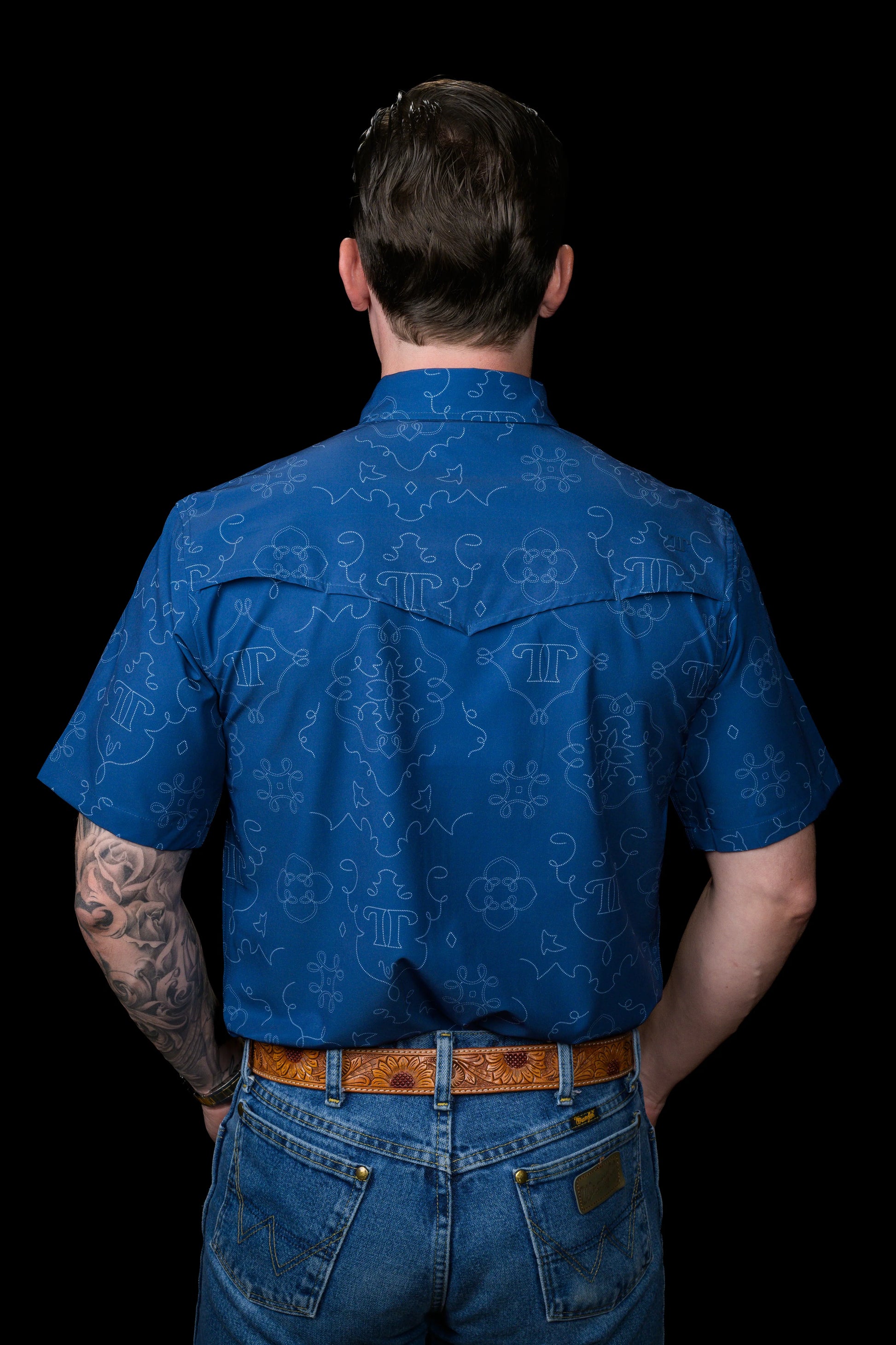 Back view of a person wearing a blue patterned Ferrell Brand shirt on a black background
