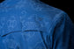 View of back yoke of a blue shirt with white pattern and Ferrell Brand logo on a black background