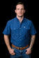 Man wearing a blue patterned Ferrell Brand shirt and jeans on a black background