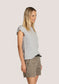 Side view of woman wearing a striped shirt and shorts on a plain background