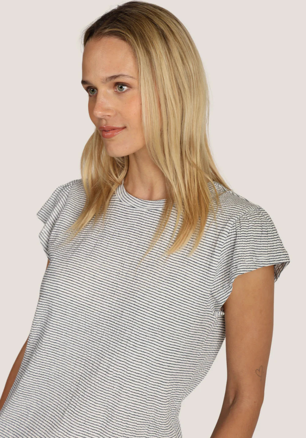 Woman wearing a black and white striped shirt against a plain background