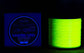 Spool of glowing green fishing line next to a label on a dark background