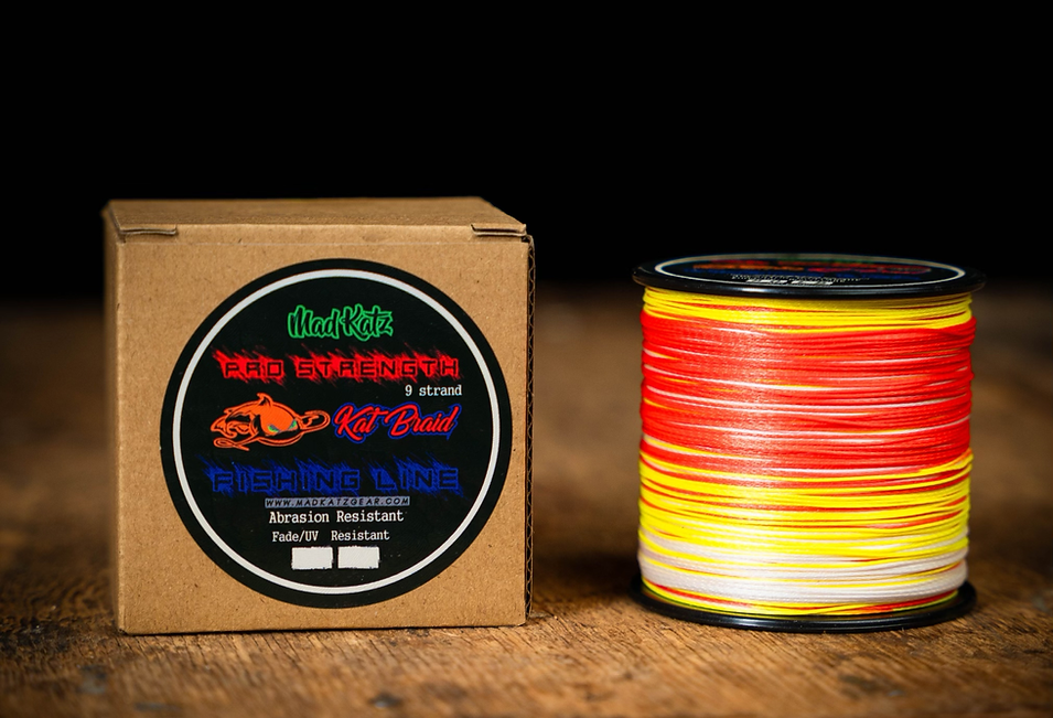 Spool of red, yellow, and white fishing line next to a cardboard box with Mad Katz Gear branding.