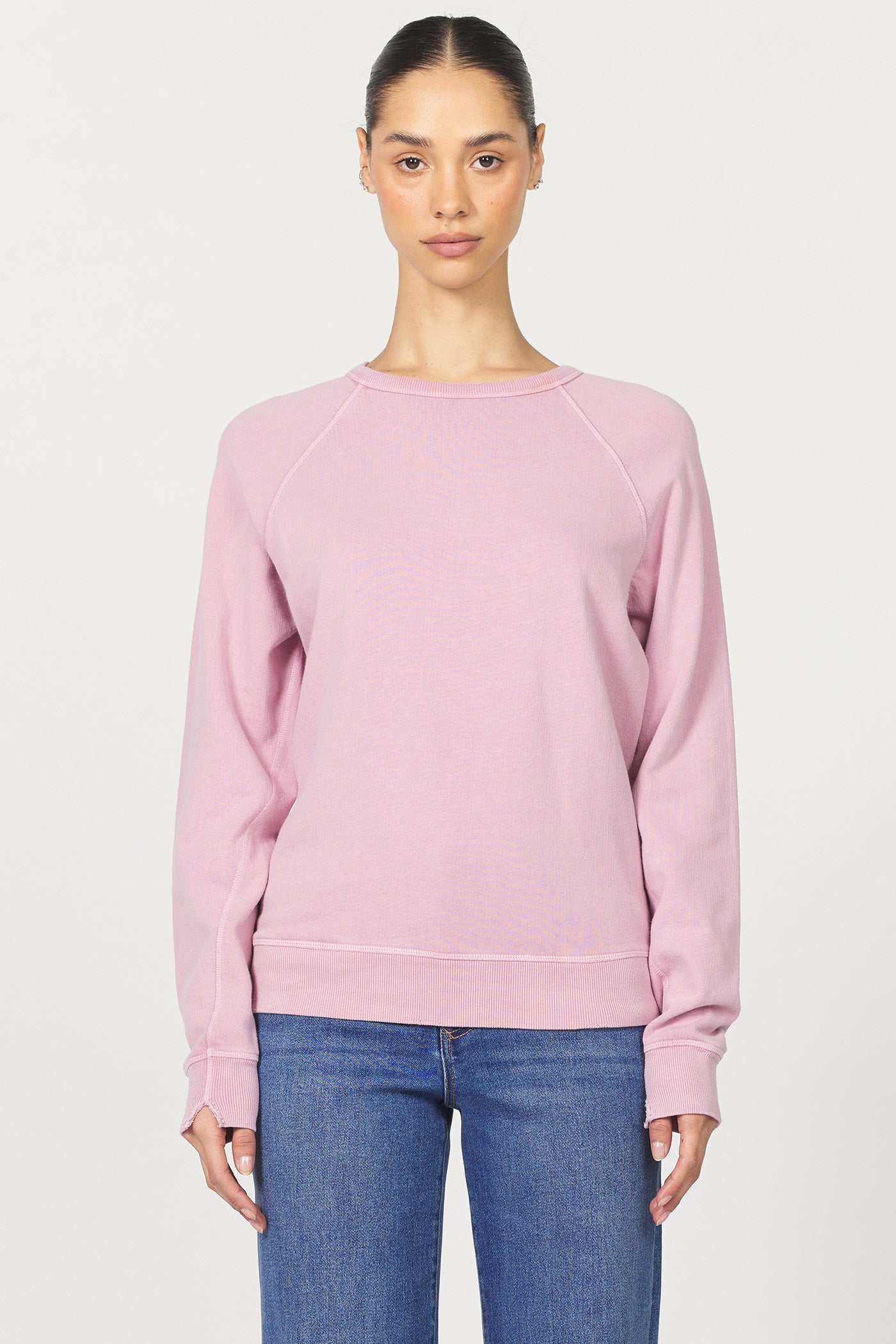 Person wearing a pink sweatshirt and blue jeans on a white background
