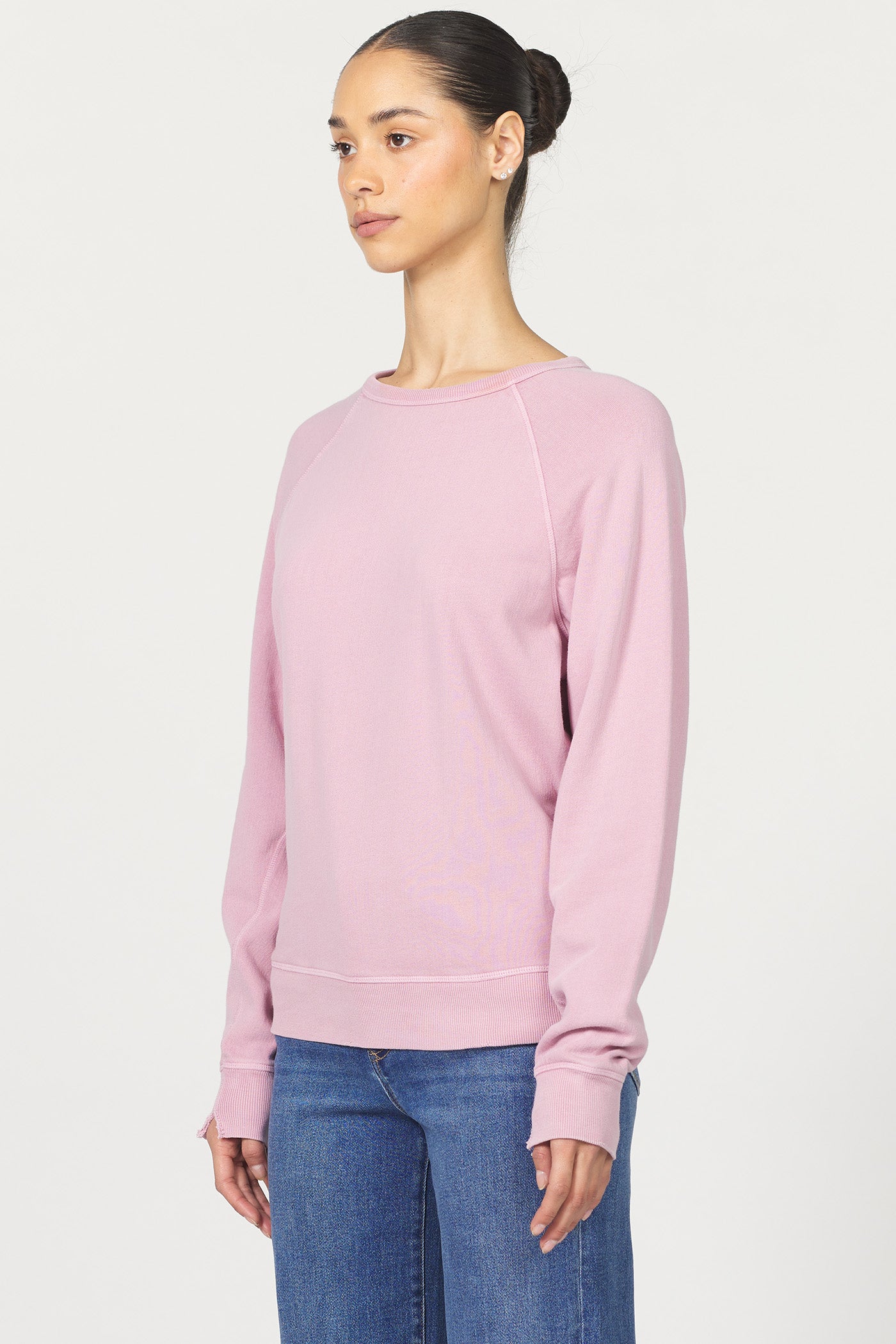 Woman wearing a pink sweatshirt and blue jeans on a white background