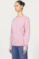 Woman wearing a pink sweatshirt and blue jeans on a white background